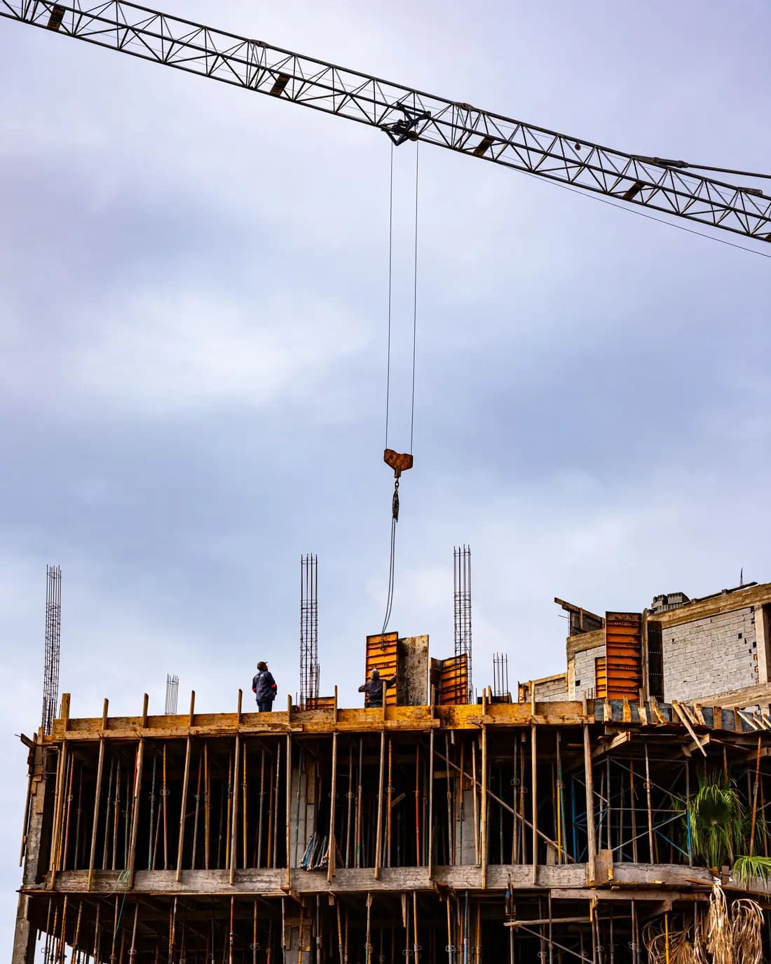 Immeuble en construction à Marrakech : une grue soulève une charge au-dessus des coffrages et des ouvriers